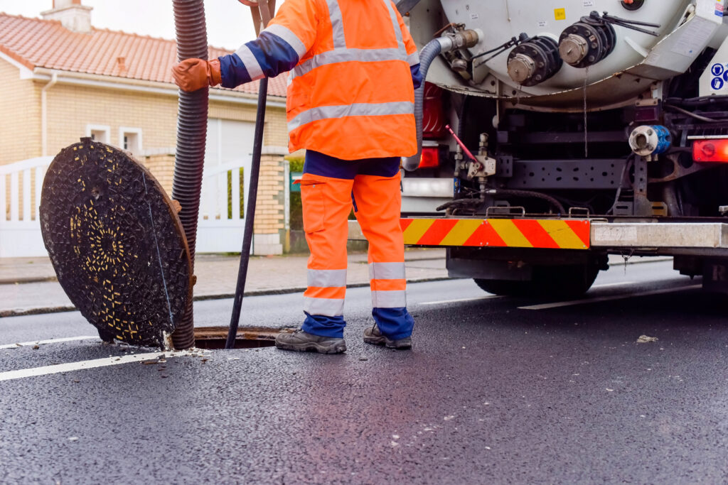 Man working sewer cover off Getty