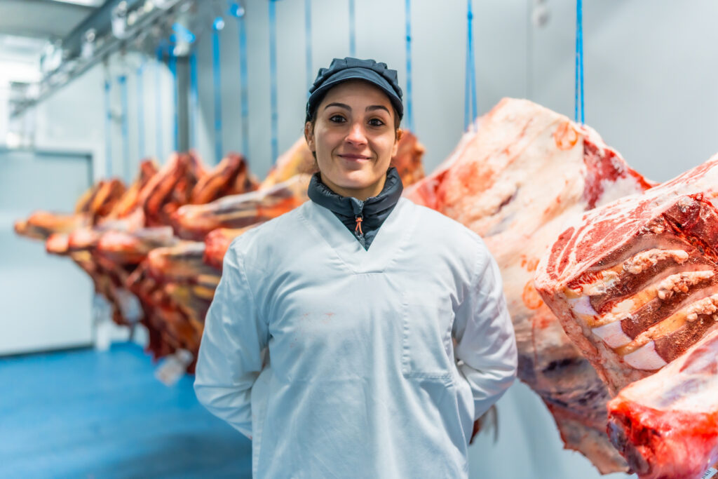 Woman butcher in a cold storage room of meat factory