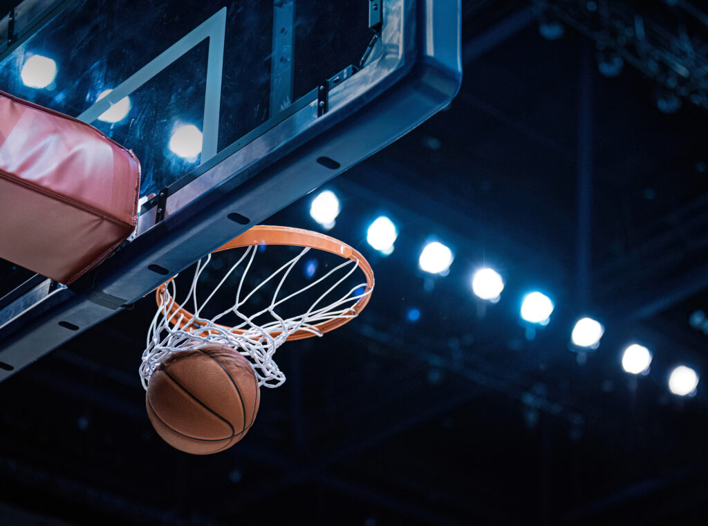 Basketball scoring a basket as it goes through the hoop